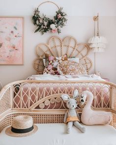 a rattan bed with pink and white decor in the corner, next to a small stuffed giraffe