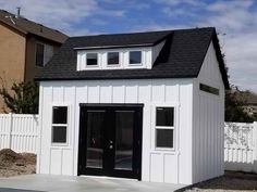 a small white shed with black doors and windows