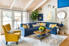 a living room with blue couches and yellow chairs