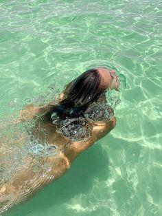 a woman swimming in the ocean with her hair blowing back