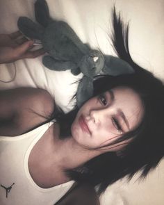 a woman laying on top of a bed next to a stuffed animal