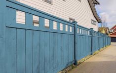 a blue wooden fence next to a white house