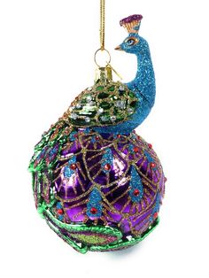 5" NOBLE GEMS GLASS PEACOCK ORNAMENT This Noble Gems™ glass peacock ball ornament by Kurt Adler is a elegant addition to your Christmas tree decor. This ornament features an ornately decorated glass ball in shades of purple and blue with a majestic peacock sitting on top. Part of Kurt Adler Noble Gems™ collection Made of glass and mica Hangs from a gold string Size: 5-inches tall Warehouse We ship from South Carolina. We ship daily Monday - Friday, excluding holidays.  Shipping to US postal serv Peacock Christmas Tree, Peacock Ornaments, Peacock Christmas, Peacock Decor, Glass Ball Ornaments, Glass Christmas Tree Ornaments, Glass Bauble, Kurt Adler, Glass Christmas Tree