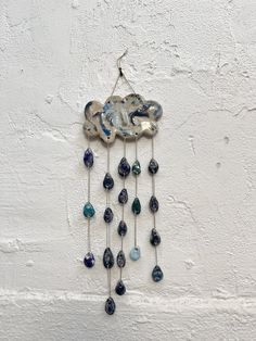 a metal wall hanging with blue and green beads on it's side, attached to a white stucco wall