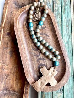 Wooden prayer beads are a beautiful way to display your faith. They can be placed on furniture, in bowls, hanging from anywhere you choose, etc. They make a beautiful gift and also great for anyone receiving a sacrament.  Each bead is approx. 3/4 inch  Hand-painted with approx. 3 inch clay cross  it also includes a miraculous medal, all beaded with jute  33 beads in total with 3 turquoise beads and 30 champagne/silver beads  Also comes with 5 prayer encouragement cards with bible verses Meditation Rosary With Wooden Beads And Cross Shape, Spiritual Rosary With Large Beads, Spiritual Rosary With Large Beads As Gift, Clay Cross, Encouragement Cards, Miraculous Medal, Prayer Beads, Turquoise Beads, Silver Beads