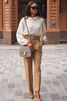 a woman is walking down the street with her hand in her pocket and holding a purse