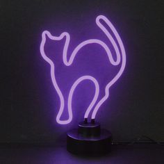 a purple neon cat lamp sitting on top of a black table next to a wall