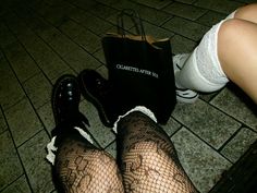 a woman's legs with fishnet stockings and high heels, holding a black bag