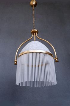 a white and gold chandelier hanging from a ceiling fixture with glass pleated shades