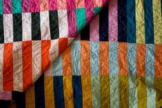 a multicolored quilt is laying on top of a tablecloth that has been folded over