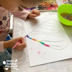 a child is painting on paper with paintbrushes