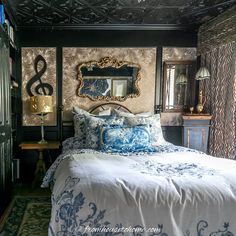 a bed with blue and white comforter in a bedroom next to a mirror on the wall