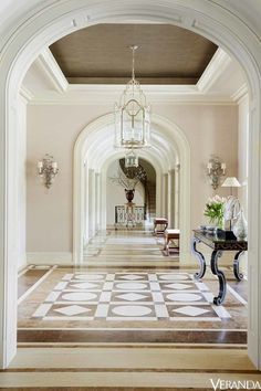 an archway leading to a foyer with chandelier and table in the center on one side