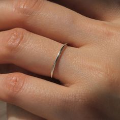 a woman's hand with a silver ring on her left thumb and the middle finger