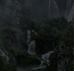 a waterfall in the middle of a forest at night