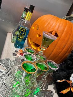 there are glasses with drinks in them on the table next to a jack - o'- lantern