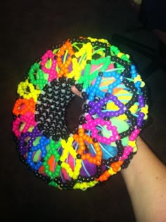 a person holding a multicolored doughnut with sprinkles on it