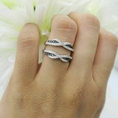 a woman's hand with two rings on it and a flower in the background