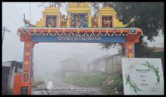 an arch with statues on it in the middle of a street and foggy sky