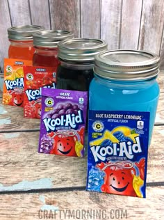 four jars filled with kool - aid candy sitting on top of a wooden table