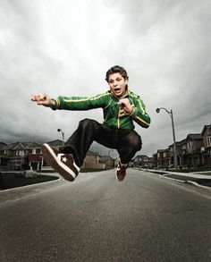 a young man is jumping in the air with his skateboard on an empty street