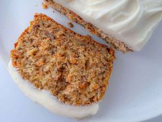 two slices of carrot cake on a white plate with cream cheese frosting next to it