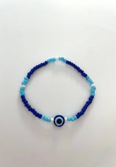 a super cute bracelet with an evil eye in the middle followed by a cute pattern of blues and white! stretchy and durable. Evil Eye Bead Bracelet, Casual Adjustable Evil Eye Bracelet With Colorful Beads, Casual Multicolor Beaded Evil Eye Bracelet, Trendy Hand-strung Blue Beads, Trendy Blue Hand-strung Beads, Casual Evil Eye Bracelet With Colorful Beads, Casual Beaded Evil Eye Bracelet As Gift, Trendy Blue Beaded Bracelets With Tiny Beads, Blue Spiritual Stretch Bracelet For Beach