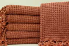 four brown towels stacked on top of each other with tasseled edges and fringes