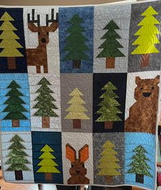 a quilt made to look like a forest scene with trees, deer and bear on it