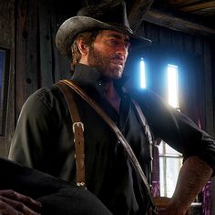 a man with a hat and suspenders is standing in front of a window holding a camera