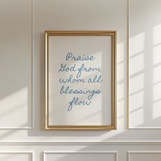 a white wall with a gold frame hanging on it and a blue quote in the middle