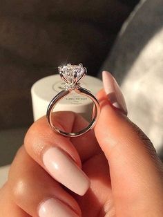 a woman's hand holding an engagement ring