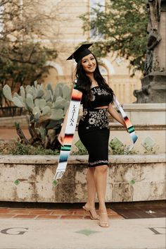 a woman in a graduation cap and gown posing for the camera with her sash around her neck