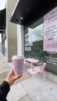 a person holding up a pink coffee cup