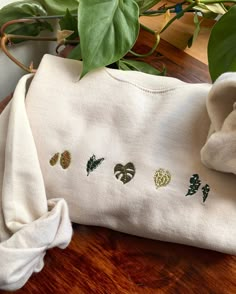 Book Embroidered Sweatshirt, Cute Crewneck Designs, Cute Houseplants, Crew Neck Embroidery Ideas, Hand Embroidered Crewneck, Embroidered Crewneck Diy, Plant Crewneck, Hand Embroidery Sweatshirt, Houseplant Leaves