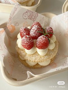 a small pastry with strawberries on top in a paper tray next to other pastries