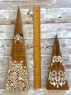 two wooden christmas trees are next to a ruler