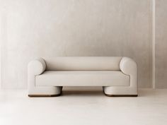 a white couch sitting on top of a hard wood floor next to a beige wall