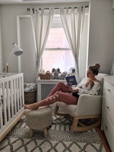 a woman sitting in a rocking chair next to a baby crib with a book on it