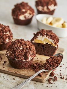 chocolate cupcakes with white frosting and banana slices on a wooden cutting board