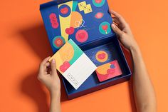 a person holding up a card in a blue box on an orange background with other cards