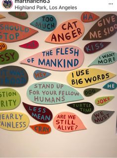 many different colored speech bubbles with words written in them on a white wall behind the sign