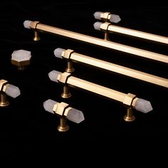 four brass handles and six white marble knobs on a black surface with dark background