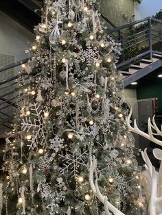 a white christmas tree with snowflakes and reindeer antlers in front of it