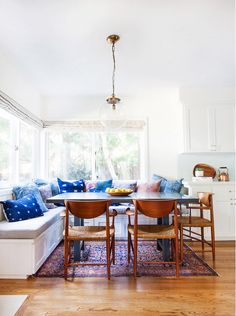 an image of a living room with blue and white pillows on the couches, dining table