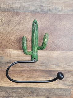 a green cactus shaped hook on a wooden surface