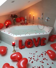 a hot tub with candles and balloons in the shape of letters that spell out love