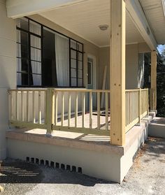 the front porch of a house with white curtains on it's windows and balconies