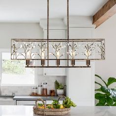 a chandelier hanging over a kitchen island with fruits and vegetables on the counter