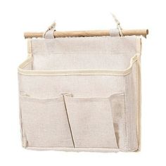 a white bag with two pockets hanging on a wooden stick and some fabric in front of it